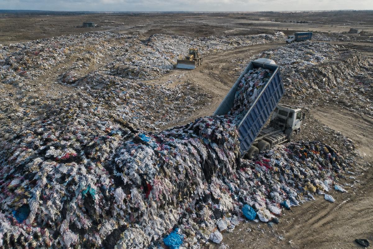 A landfill piled with discarded clothing and textiles, highlighting why reuse matters